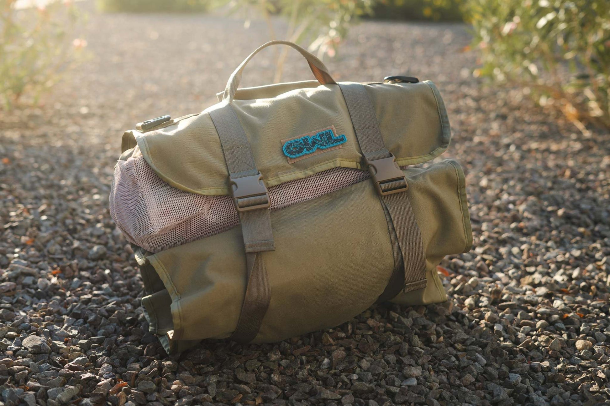 Compact olive green MOLLE roll-up bag for Overland INEOS SUV Recovery Kit on rocky ground outdoors