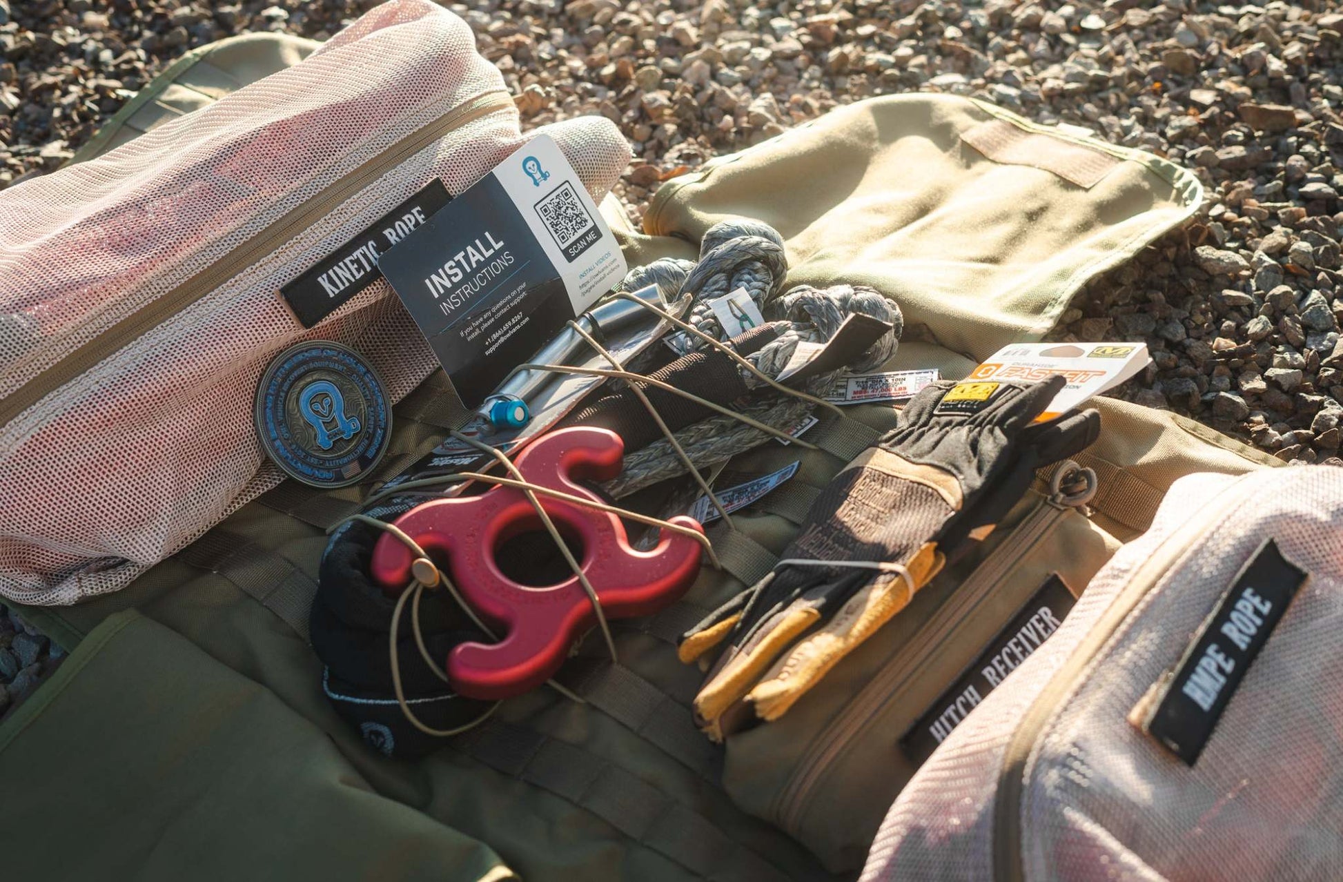 Overland INEOS SUV recovery kit with kinetic rope, gloves, modular MOLLE bag, and hitch receiver on gravel background