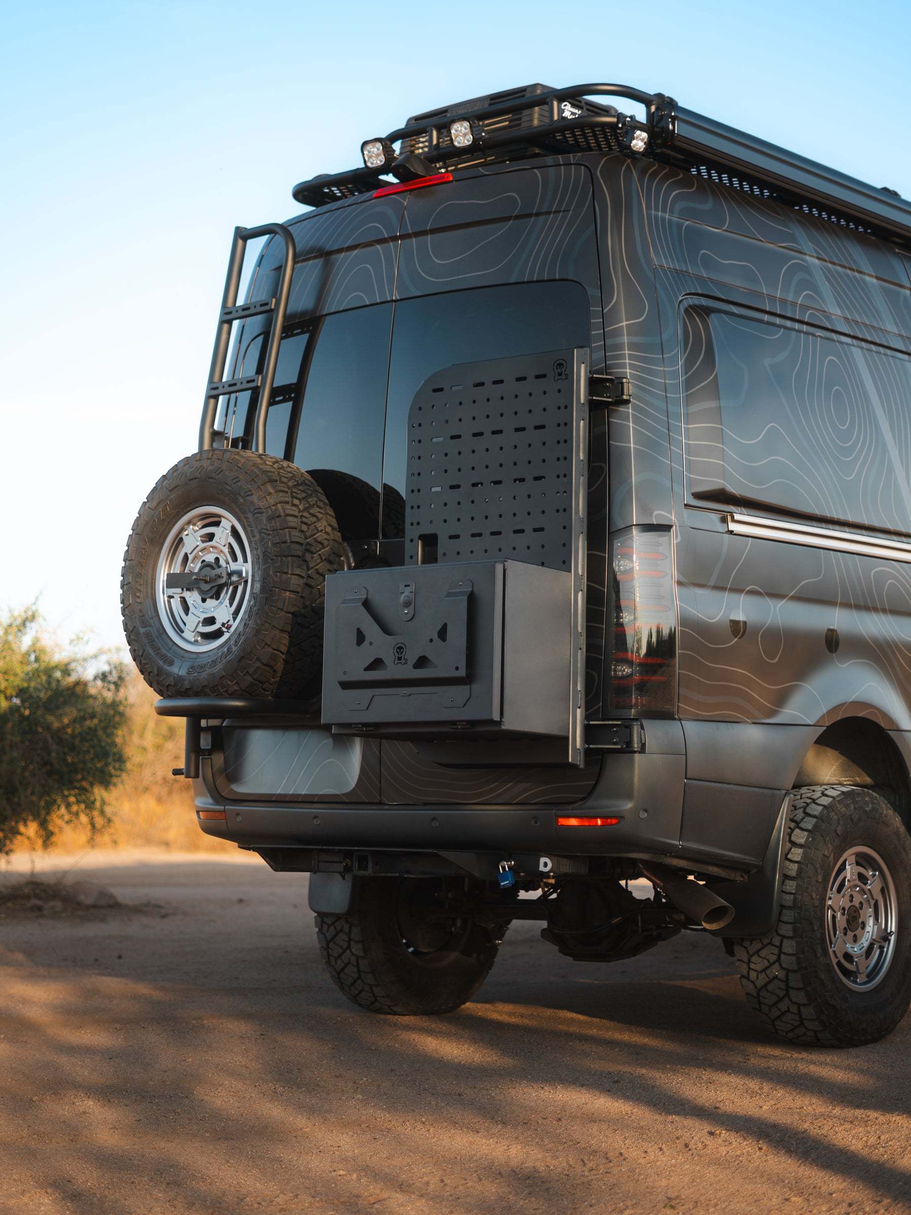 Medium Expedition Cargo Box mounted on rear of rugged off-road van with spare tire and ladder accessory