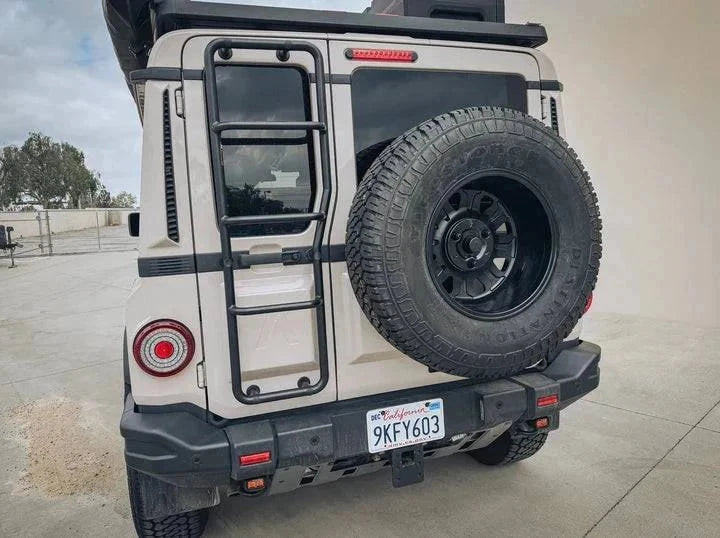 Leitner Designs Grenadier Euro Tire Relocation Bracket mounted on rear of off-road vehicle with tire and ladder.