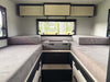 Interior of OTX Tiffin camper van showing twin beds with storage and window view