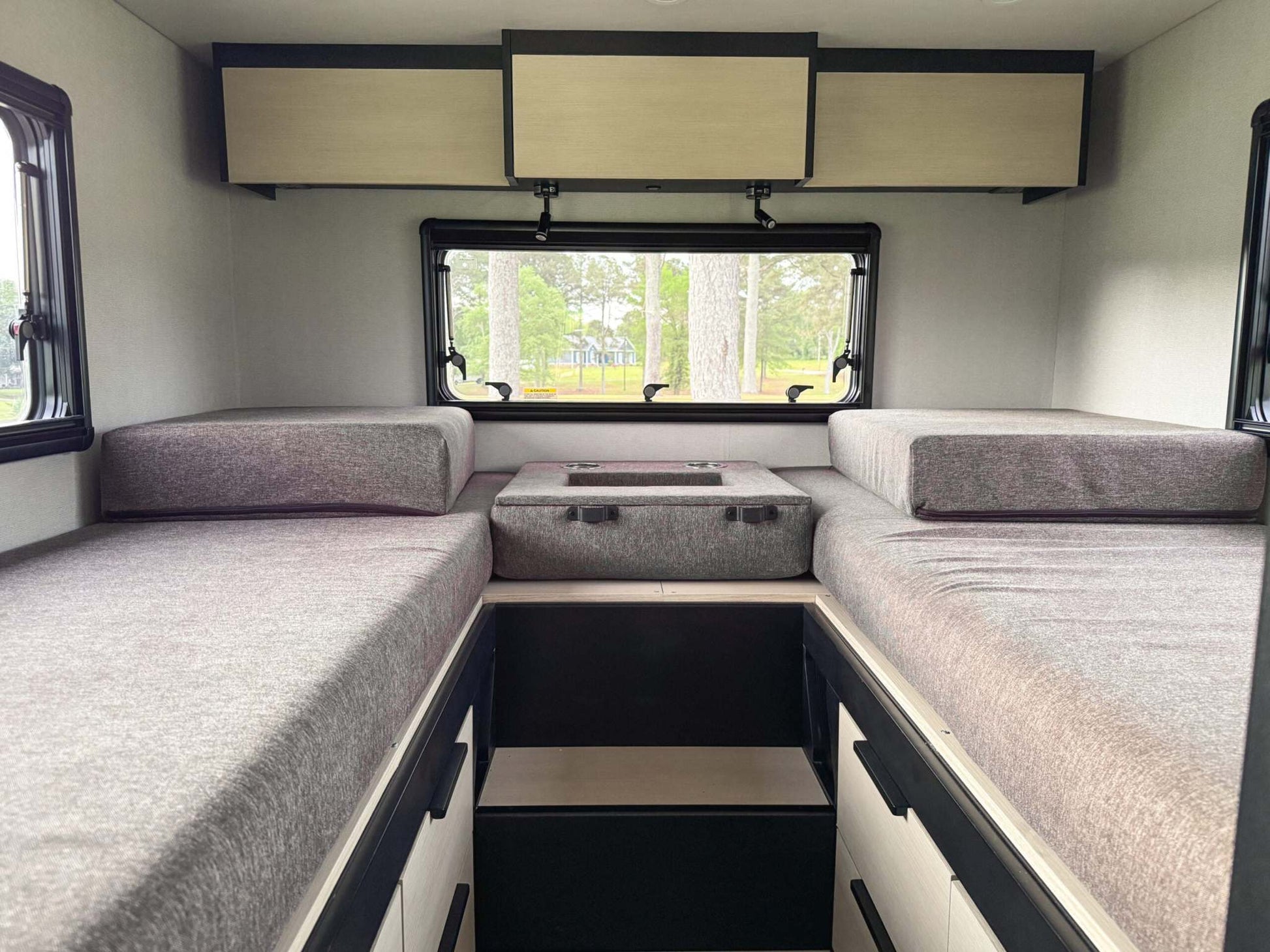 Interior of OTX Tiffin camper van showing twin beds with storage and window view