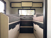 Interior view of OTX Tiffin motorhome featuring twin beds with storage drawers and overhead cabinets.
