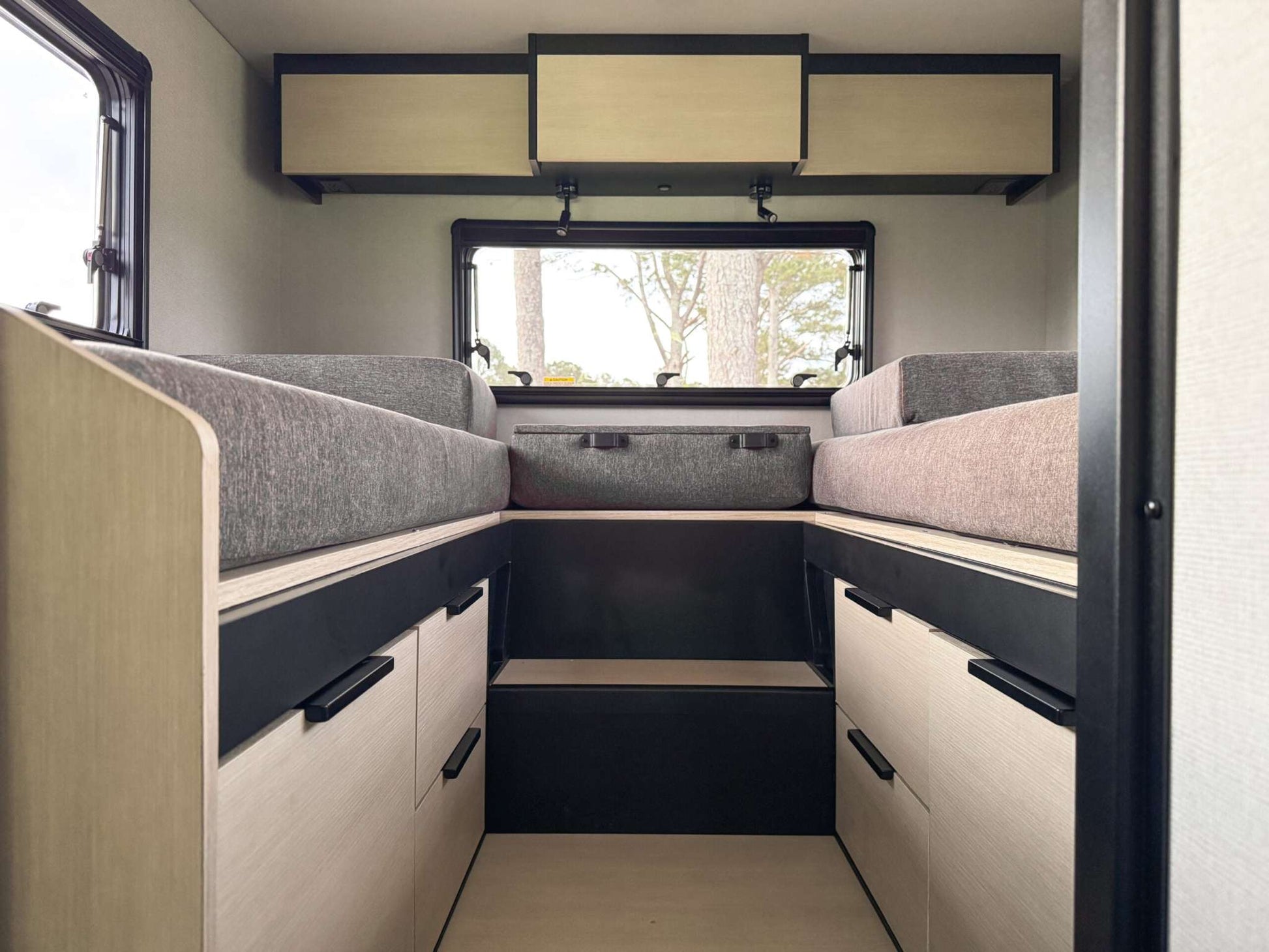 Interior view of OTX Tiffin motorhome featuring twin beds with storage drawers and overhead cabinets.