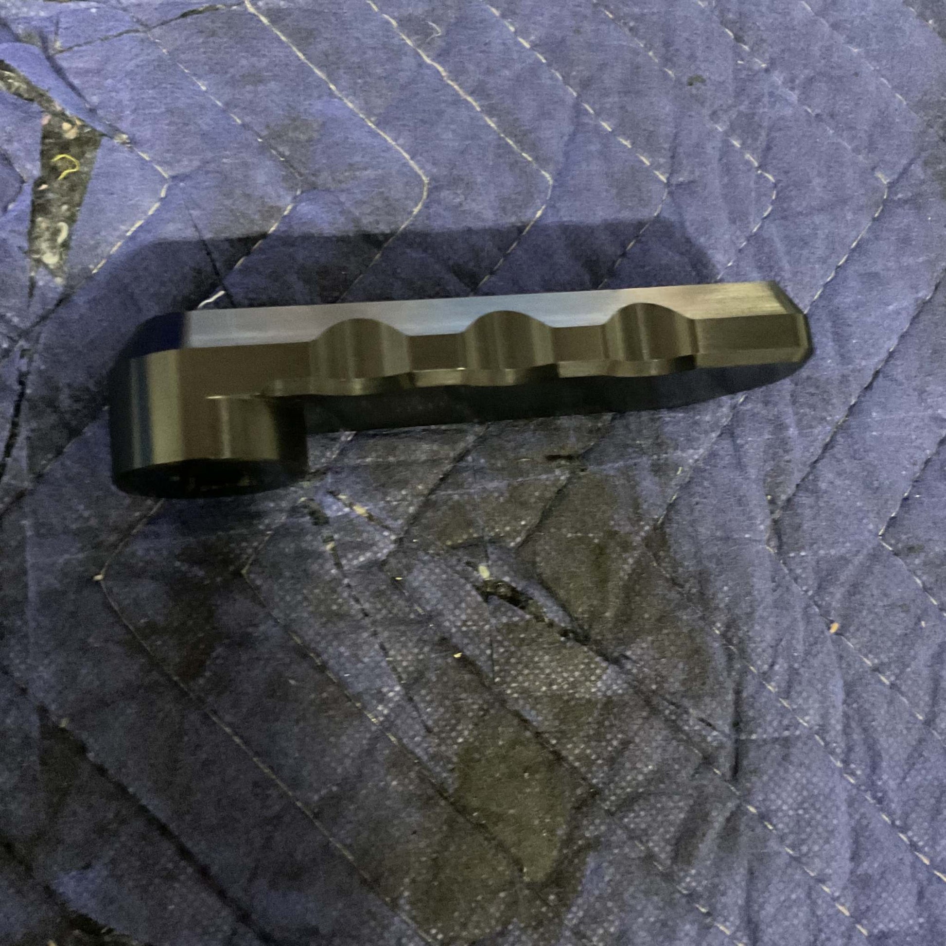 Black Grenadier Hood Release Handle designed for durability and off-road utility placed on a blue quilted protective mat.
