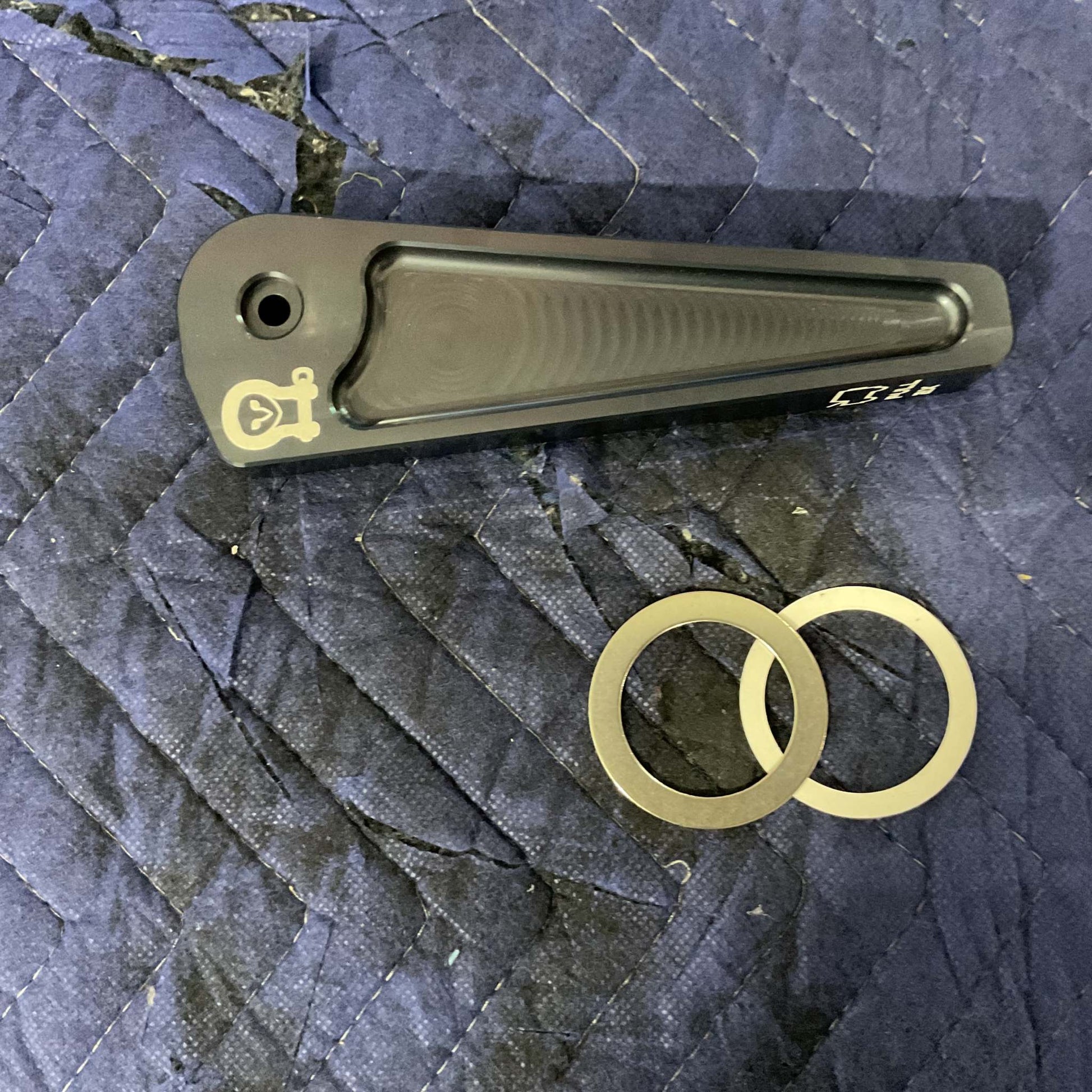 Grenadier Hood Release Handle in black with two metal washers on a blue quilted surface