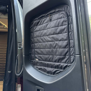Insulated black Sprinter rear window cover with zippered access installed on van door for temperature control and privacy