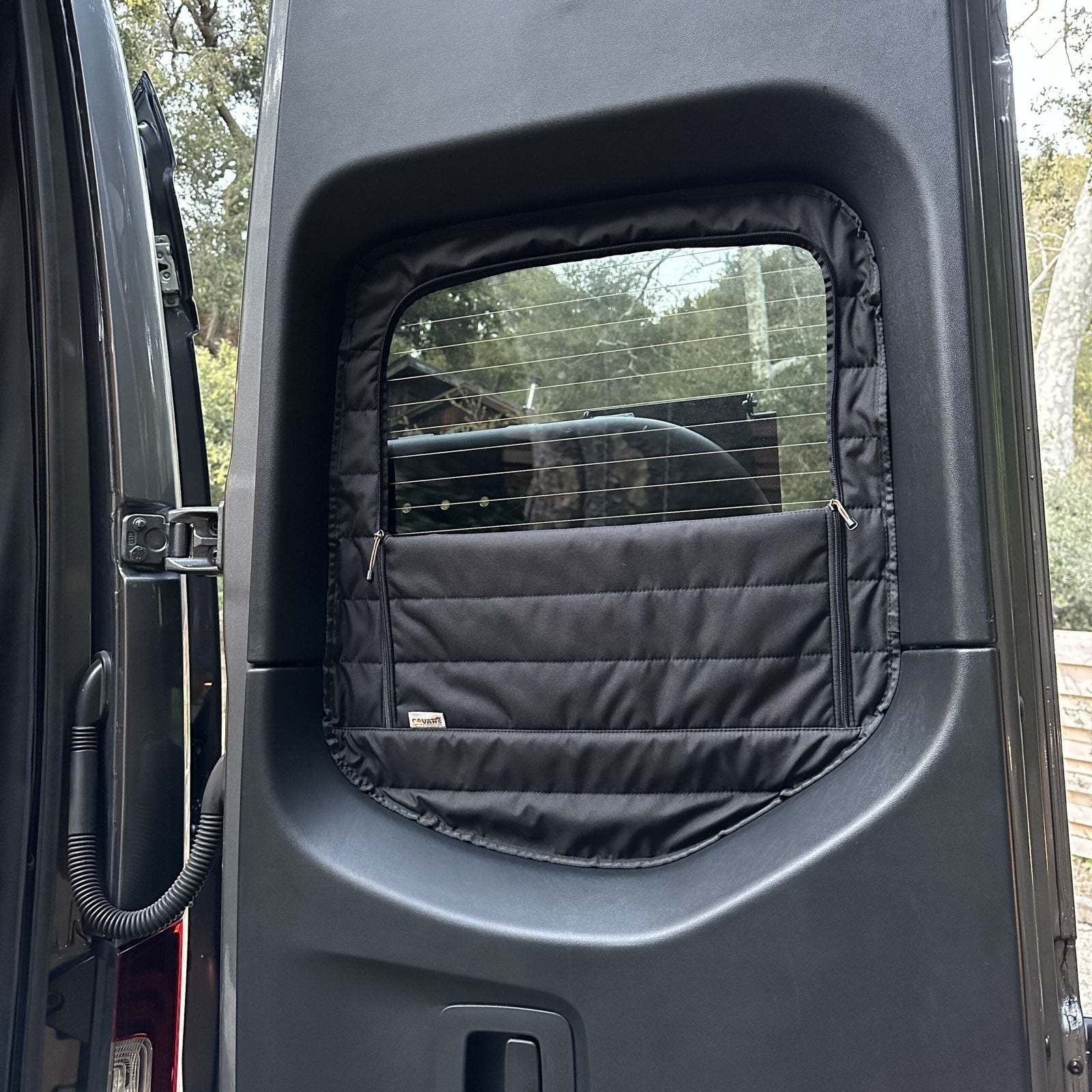 Insulated black Sprinter rear window cover with zippered access for airflow and privacy, designed for temperature control and easy installation.