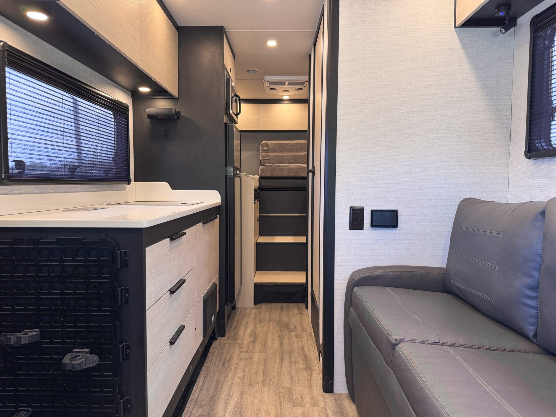Interior view of OTX Tiffin motorhome featuring modern kitchen, wood flooring, and comfortable seating area.
