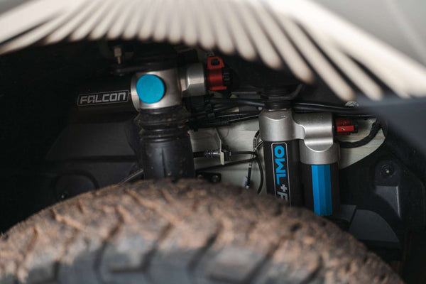 Close-up of Owl x VanCraft Wasatch Halo Sprinter suspension system behind rugged off-road tire