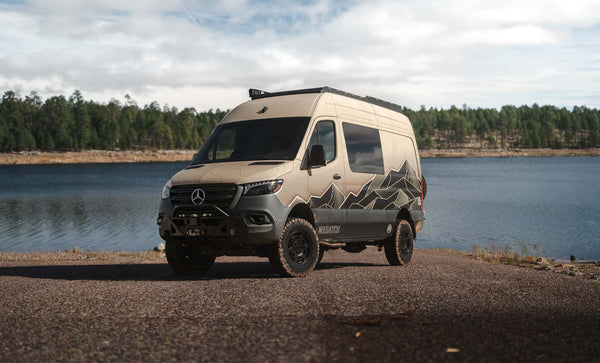 Owl x VanCraft Wasatch Halo Sprinter van with mountain graphics parked by lake in wilderness