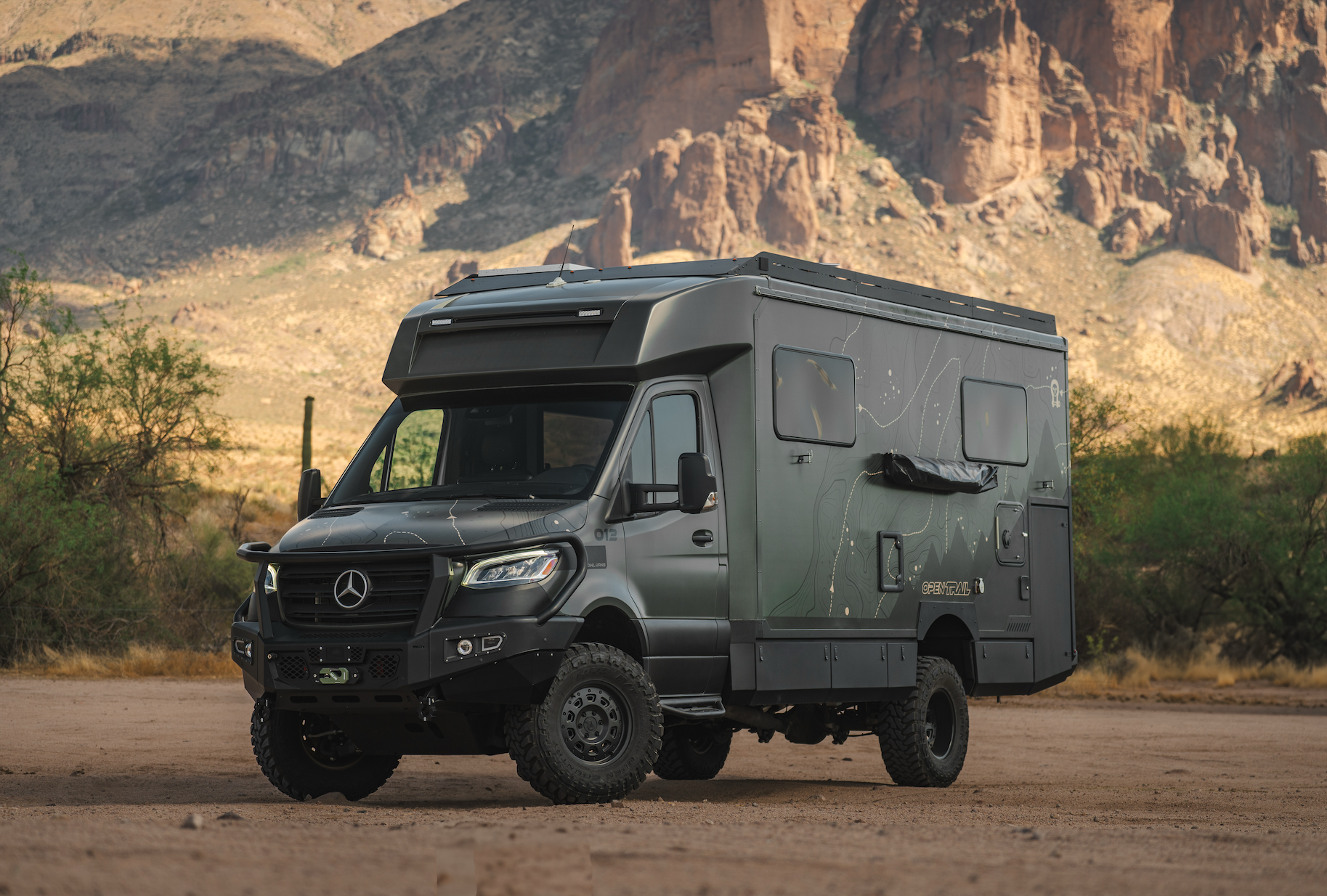 OTX Tiffin Open Trail adventure van parked in desert landscape with rugged terrain and rocky cliffs in background