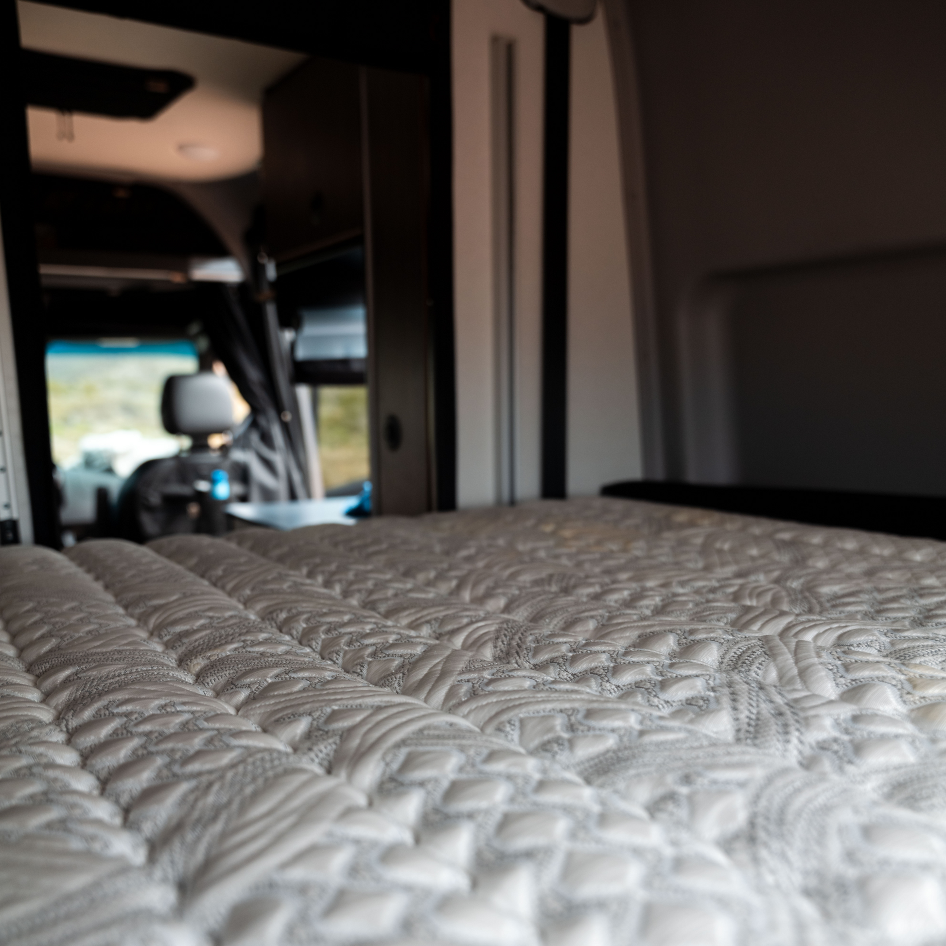 Close-up of ULTRA Luxe Mattress with detailed quilting inside a van interior.