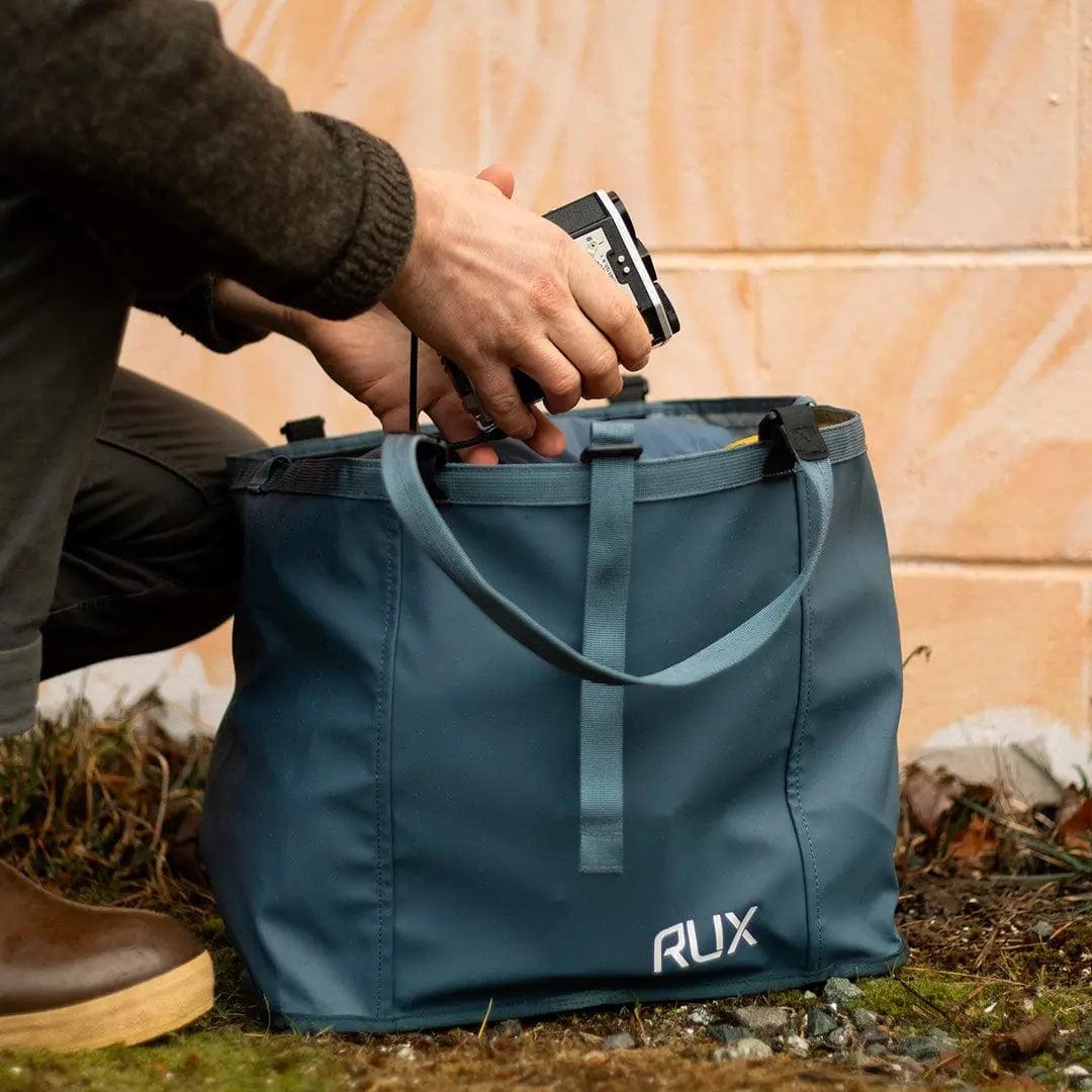 RUX 25L Bag in blue being packed with a camera, compact and versatile storage bag for easy carrying