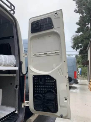 Sprinter van rear door with mounted Molle panels for functional storage.