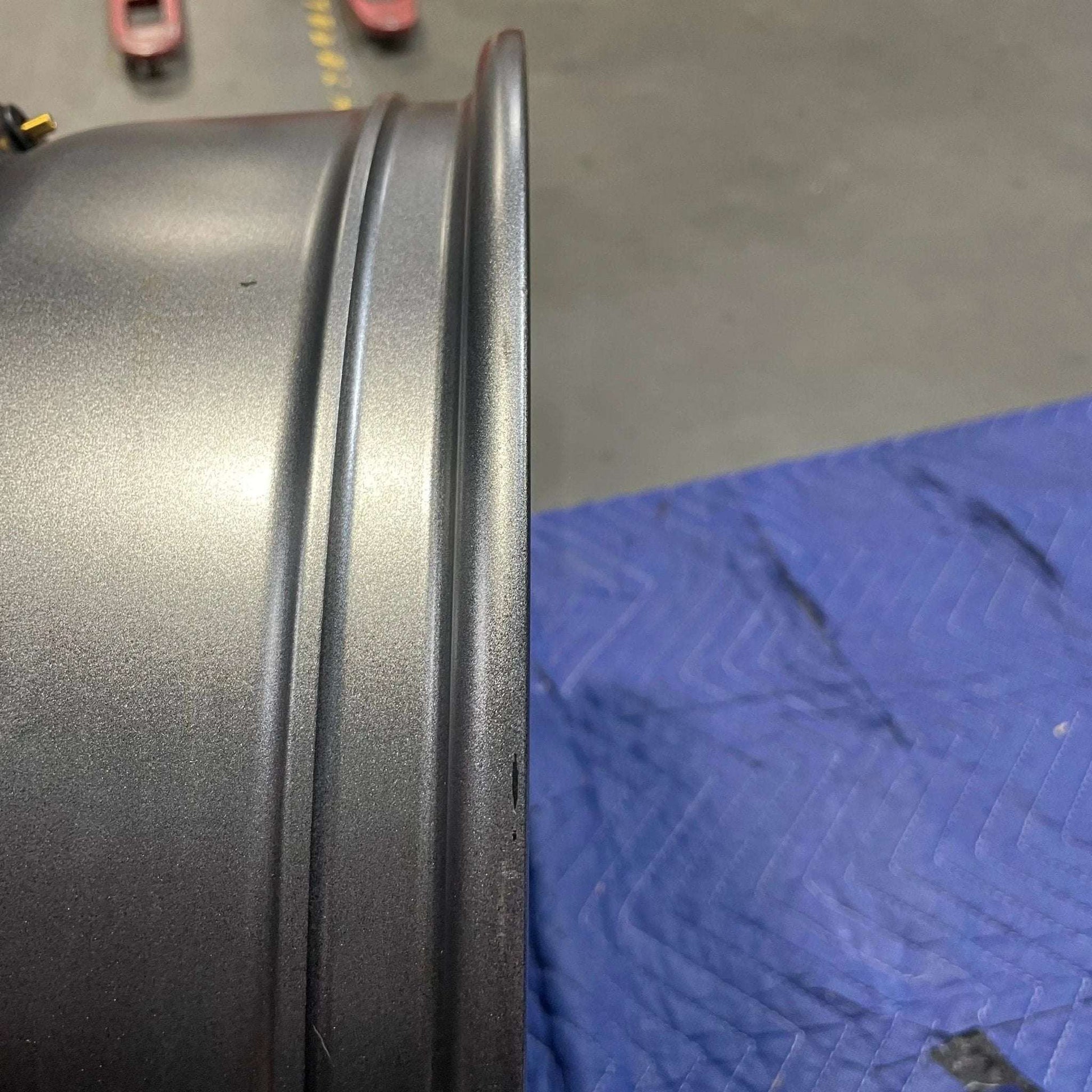 Graphite grey Talon Transit AWD wheel rim with minor scuffs on a blue padded surface.