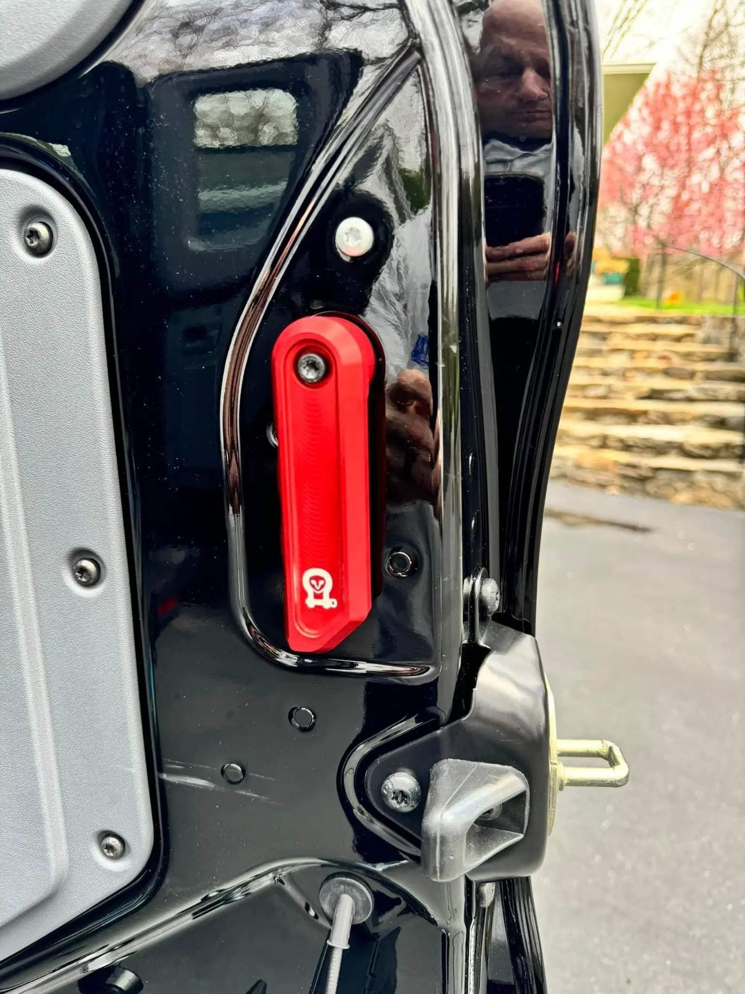 Red aluminum Grenadier rear door handle mounted on black vehicle door panel