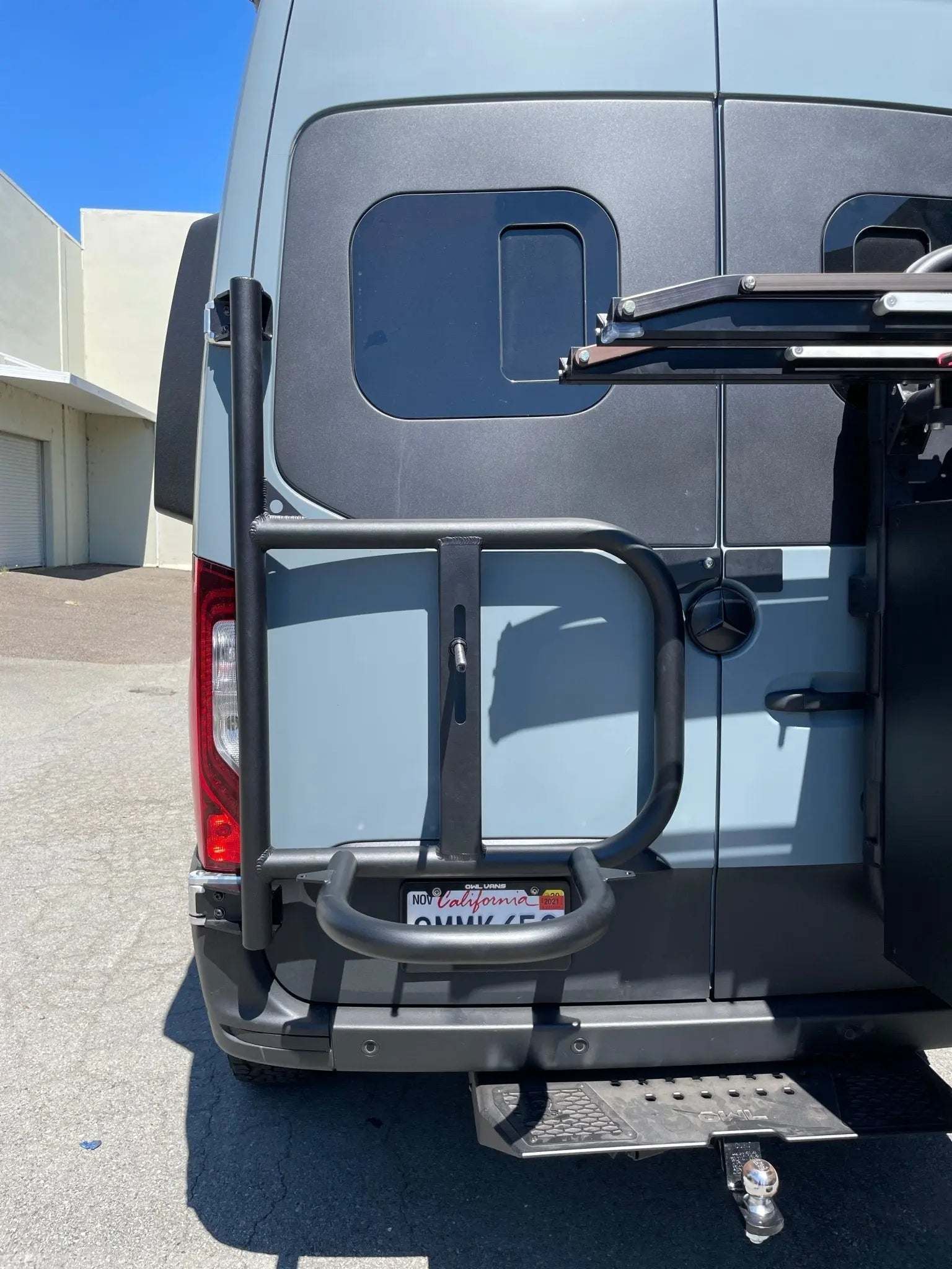 Expedition Tire Carrier on 2019+ Sprinter van, rear-mounted for full-size spare wheel.