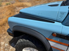 Close-up of blue INEOS Grenadier with black Grenadier Fender Armor Plates on front fender for rugged off-road protection