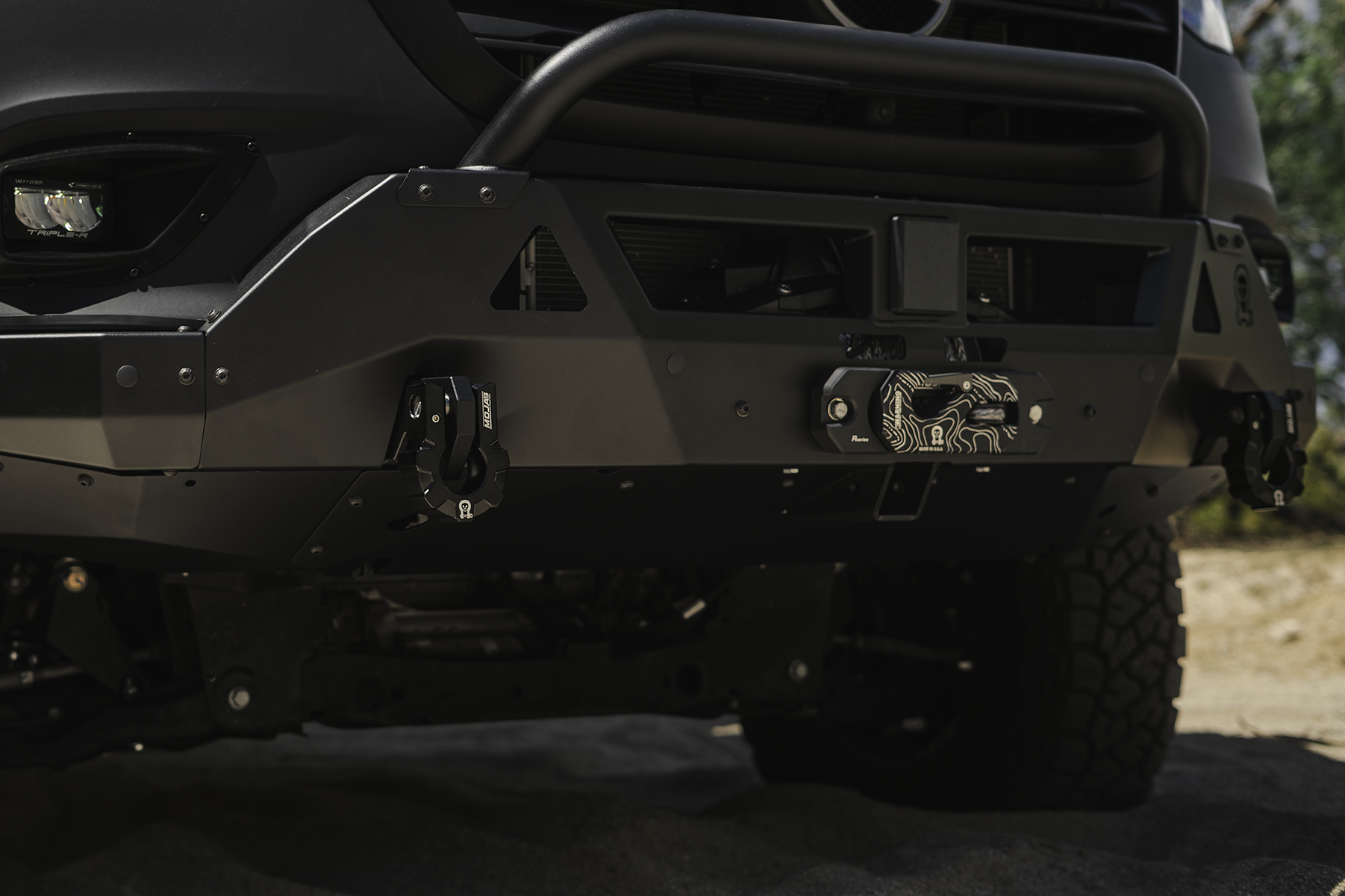 Close-up of black 9-ton aluminum D-shackle set with owl logo mounted on off-road vehicle bumper for heavy-duty recovery