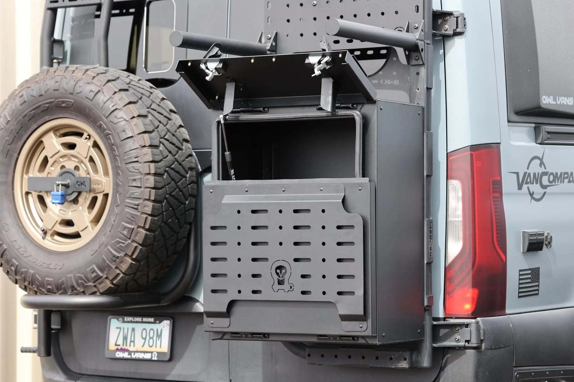 Durable black metal van storage box mounted on rear of adventure van next to spare tire