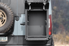 Open box showing open Owl Monster 30 van storage box mounted on rear door of adventure van next to spare tire.
