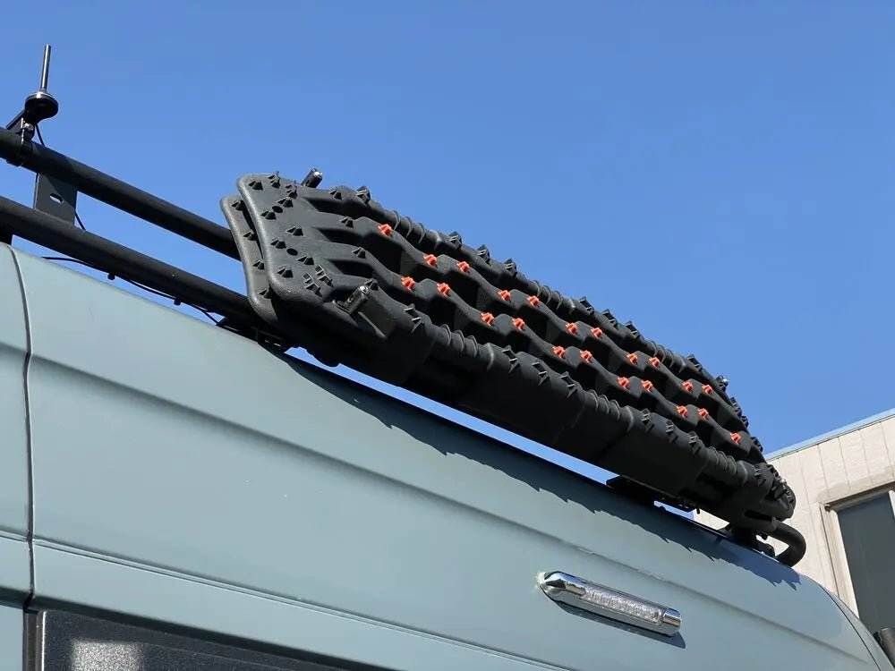 Roof rack traction board mount holding recovery boards on vehicle.