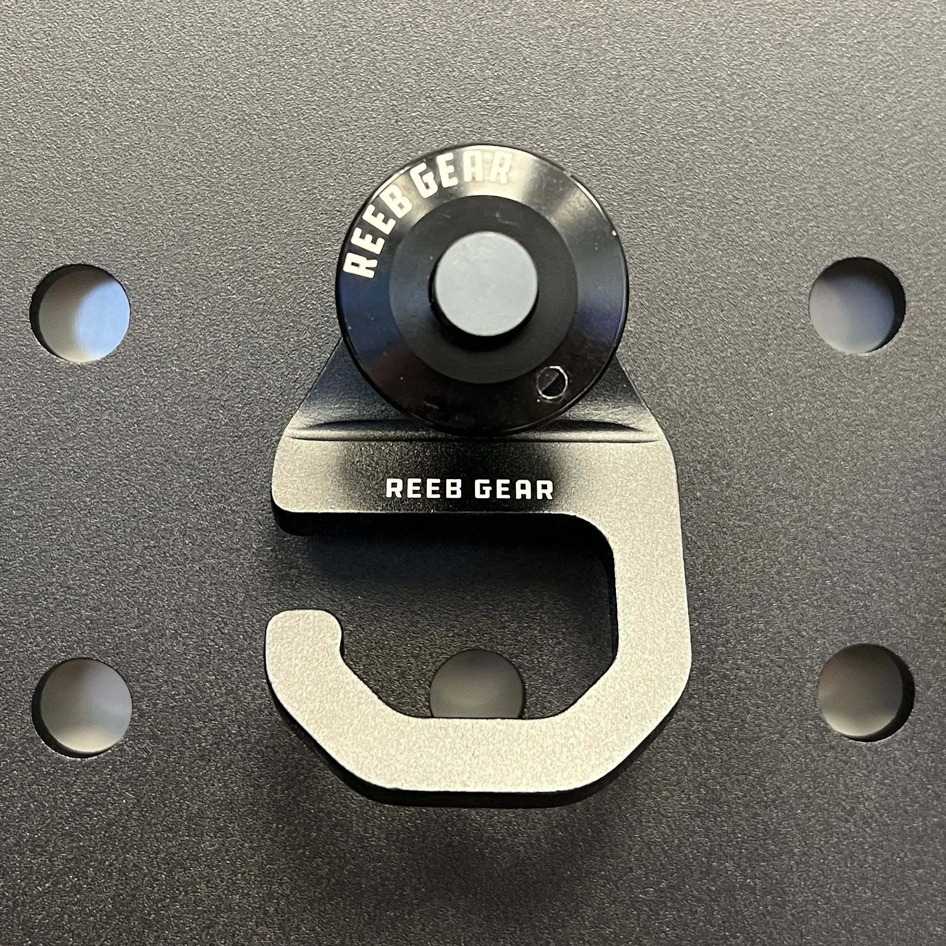 Sherpa Quick Release Hook by Reeb Gear mounted on a perforated panel for secure gear attachment and easy release.