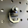 Sherpa Quick Release Hook in anodized aluminum attached to a black panel with circular cutouts for secure gear attachment