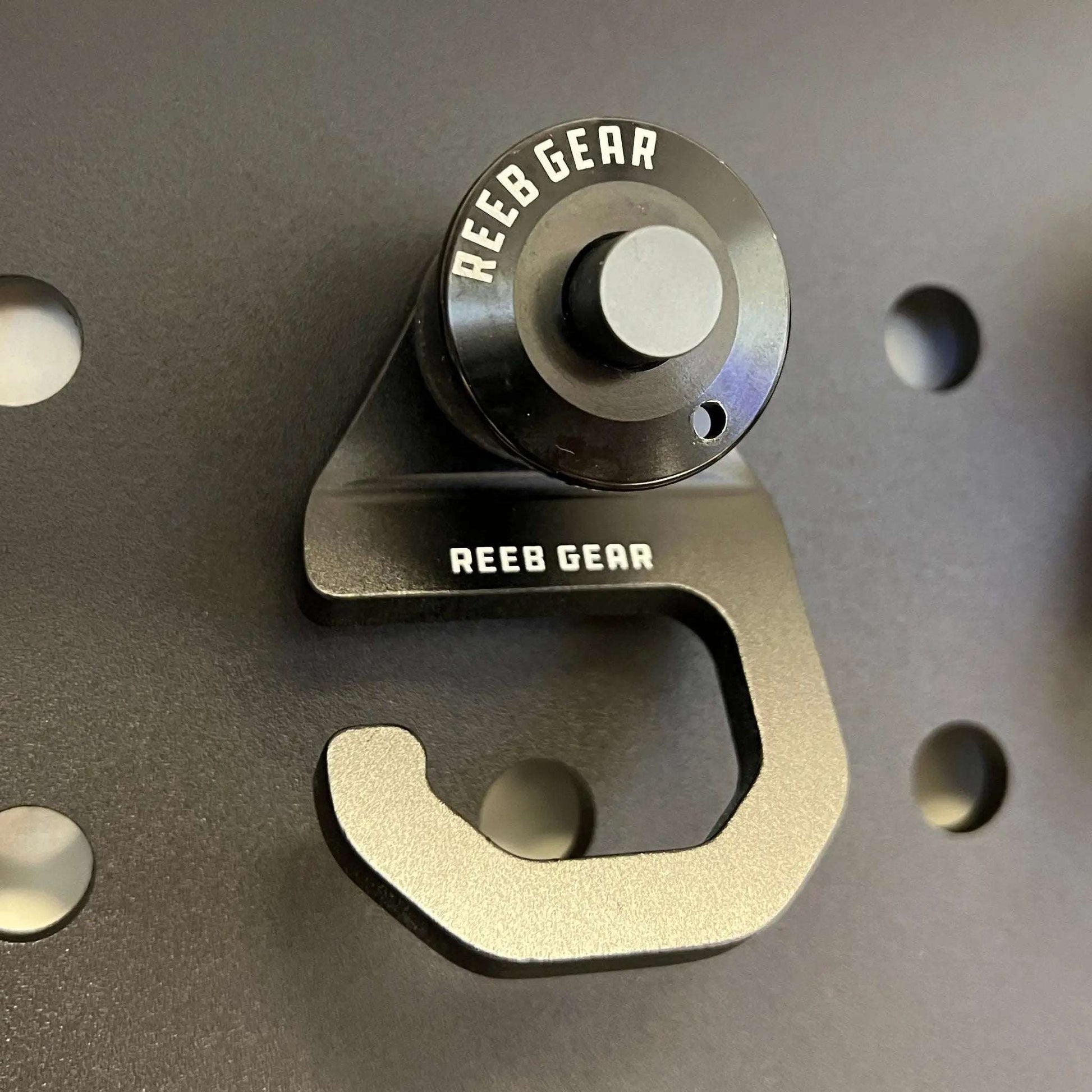 Reeb Gear Sherpa Quick Release Hook in anodized aluminum with push-button release on panel cutout for secure gear attachment