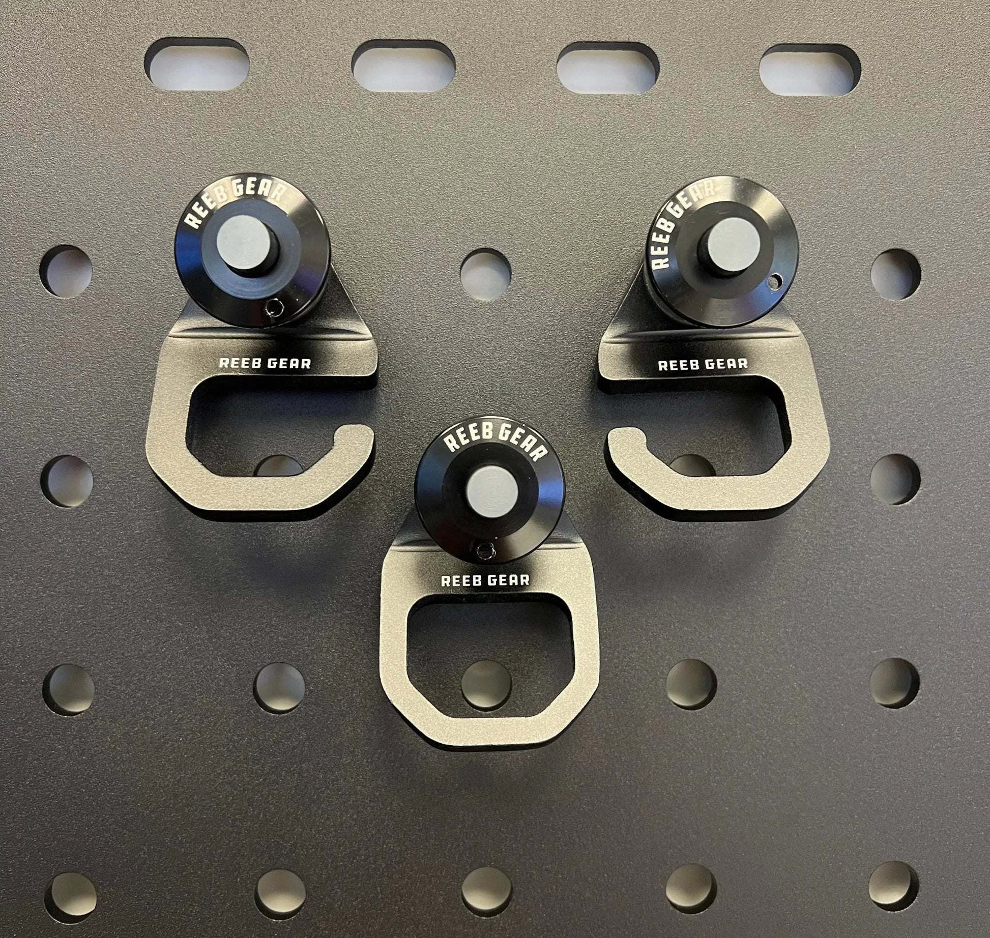 Three Sherpa Quick Release Hooks by Reeb Gear mounted on a perforated metal panel