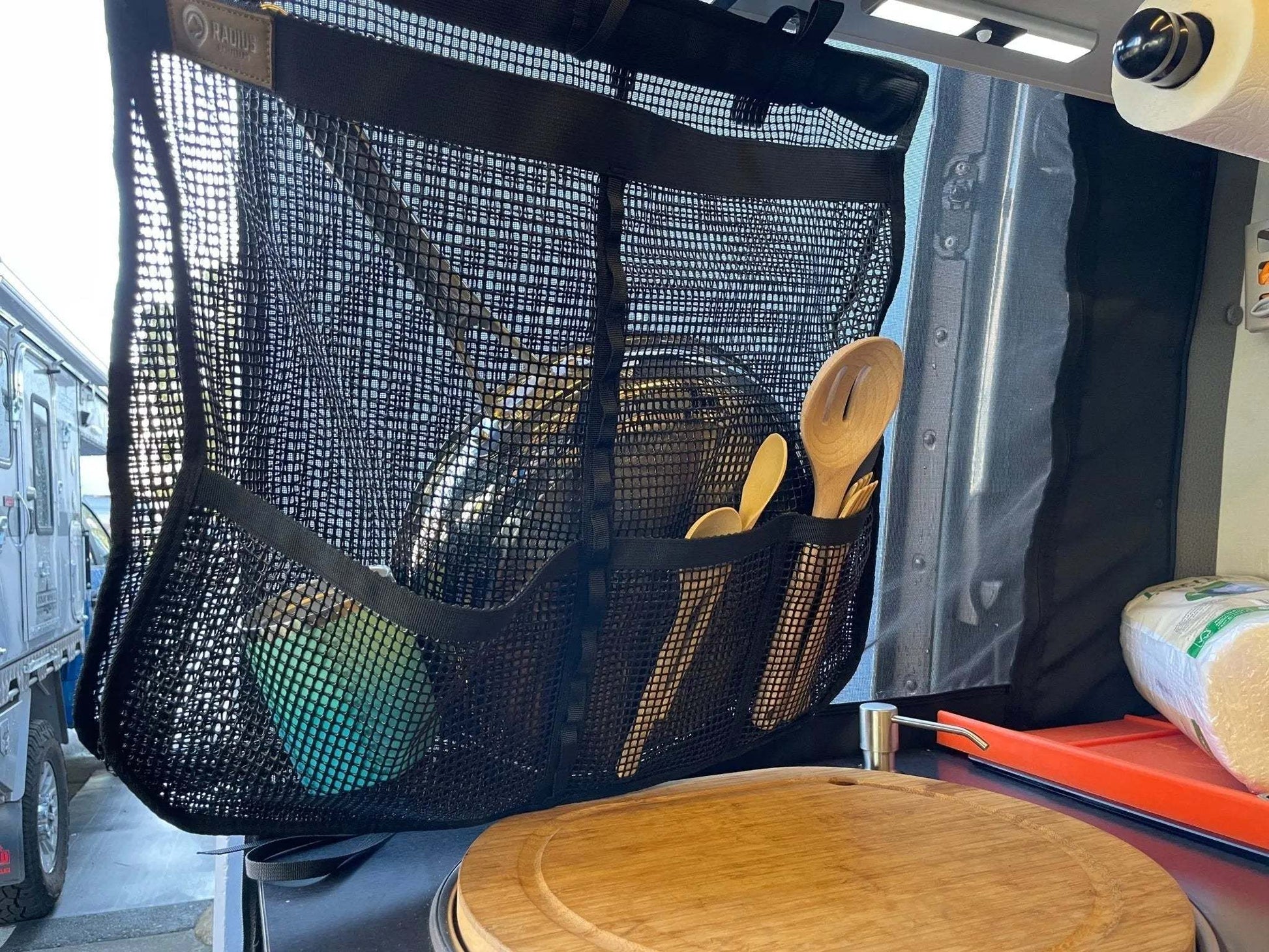 Breathable mesh camp dish drying bag hanging inside a vehicle, used for drying and storing dishes.