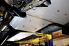 Underbody view of a 4x4 Sprinter fitted with a 1/4" thick aluminum transmission and transfer case skid plate for drivetrain protection.
