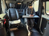 Interior view of a Sprinter van featuring a Vannon B-Pillar Mount with a fold-out table and a person seated using a phone, showcasing durable and functional overland setup equipment.