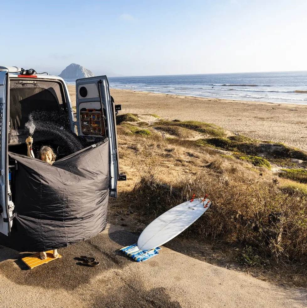 Vanlife shower curtain providing privacy and splash protection, set up by the beach.