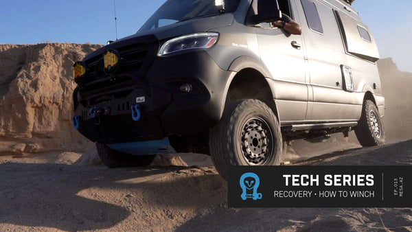 Sprinter van equipped with off-road recovery gear navigating rocky terrain in desert setting