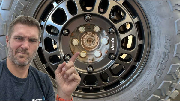 Man pointing at rusty Sprinter van hub on black Reika wheel with tire visible