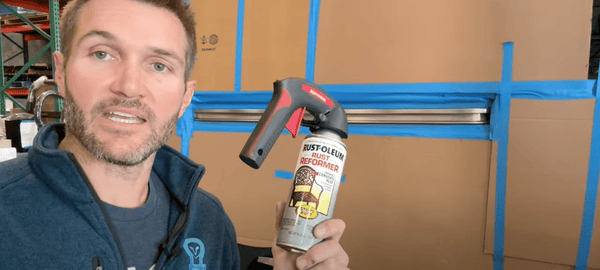Man demonstrating Rust-Oleum Rust Reformer spray for blackout painting Sprinter sliding door track taped off with blue painter's tape.