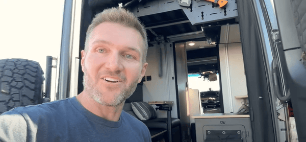 Man demonstrating Keep Your Rear Sprinter Doors Open product inside a van with open rear doors and interior view.