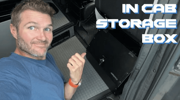 Man pointing to in-cab extra storage box installed inside a Sprinter van for added gear organization.