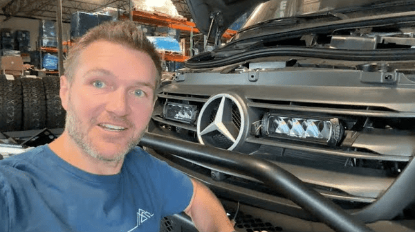 Man showing painted Mercedes Sprinter van emblem with matte finish in workshop setting