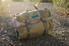 Compact olive green MOLLE roll-up bag for Overland INEOS SUV Recovery Kit on rocky ground outdoors