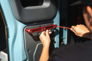 Red Grenadier Rear Grab Handle being installed on vehicle door interior panel by person