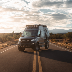 Sprinter van equipped with Arrow Lifted Pro suspension system on desert road at sunset