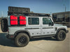 Silver off-road vehicle with two red 20L jerry cans mounted on a Grenadier Jerry Can Holder attached to the side rear panel.