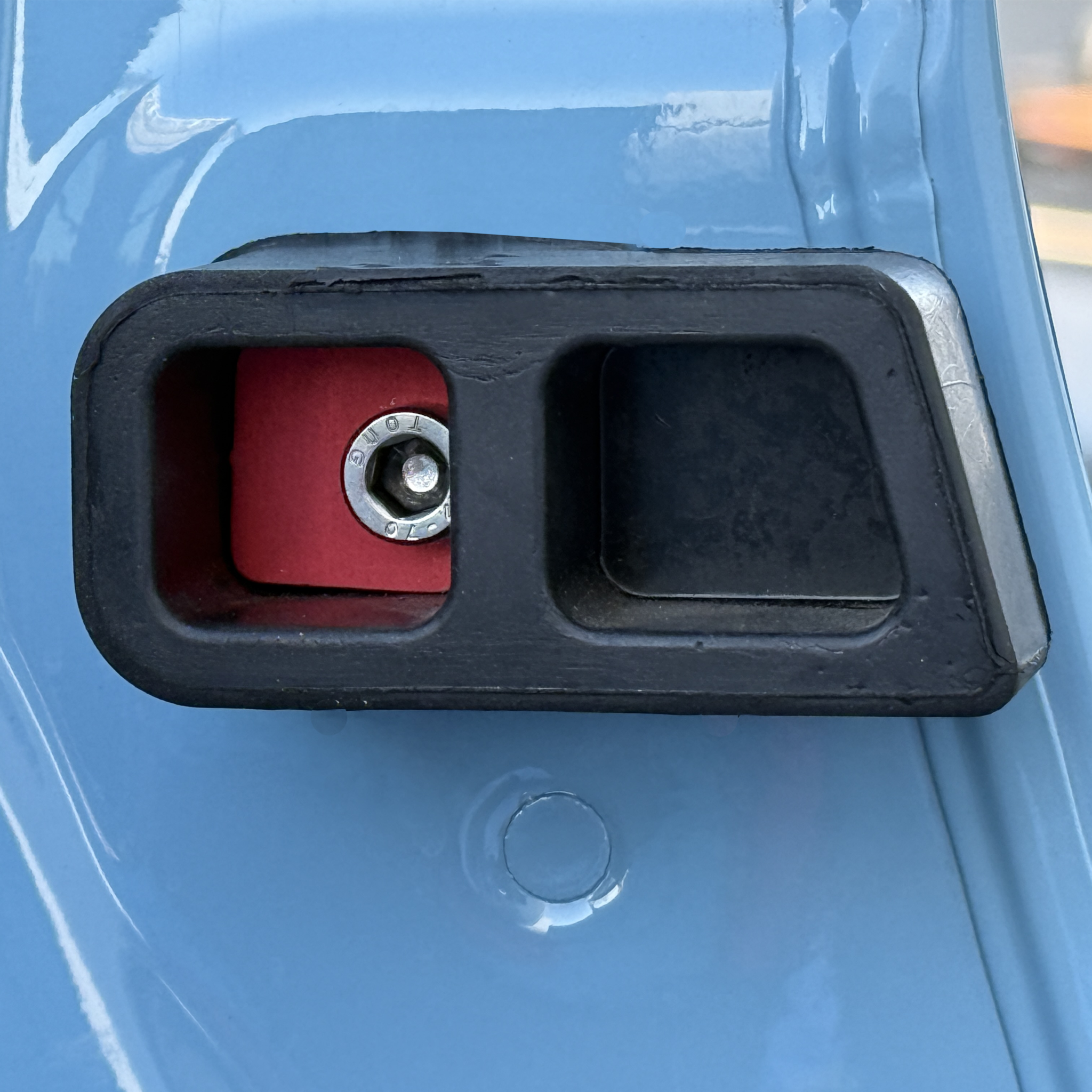 Close-up of rear door washer and rubber bumper on blue INEOS Grenadier vehicle door designed to protect paint and secure bumper.