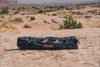 Outer Limits Camp Chair folded in black water-resistant carrying bag on rocky desert terrain