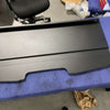 Black powder-coated Sprinter Headliner Shelf designed for 2019+ models, shown on a blue padded surface with a chair and workshop background.