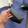 Hand holding a black lightweight billet aluminum Seat Back Locker component for Sprinter storage on a blue padded surface with notes in the background