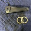 Grenadier Hood Release Handle in black with two metal washers on a blue quilted surface